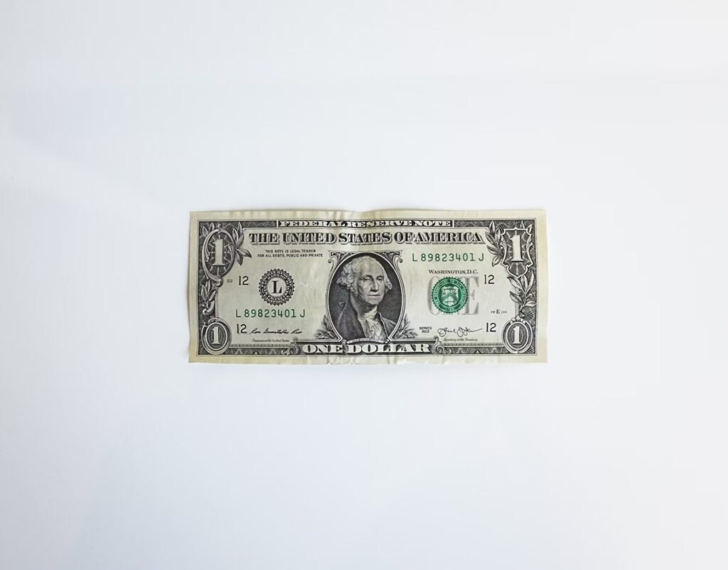 A one-dollar bill placed on a white surface, highlighting the unique design elements