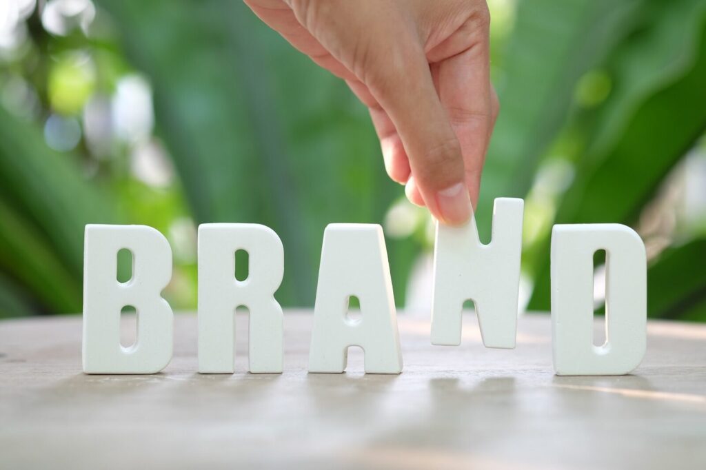 A hand arranging the word brand using white letters