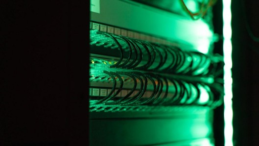 Technician installing fiber optic network cables in a commercial server room