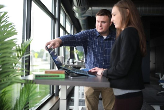 Two agency operators comparing software options on a tablet at a standing desk